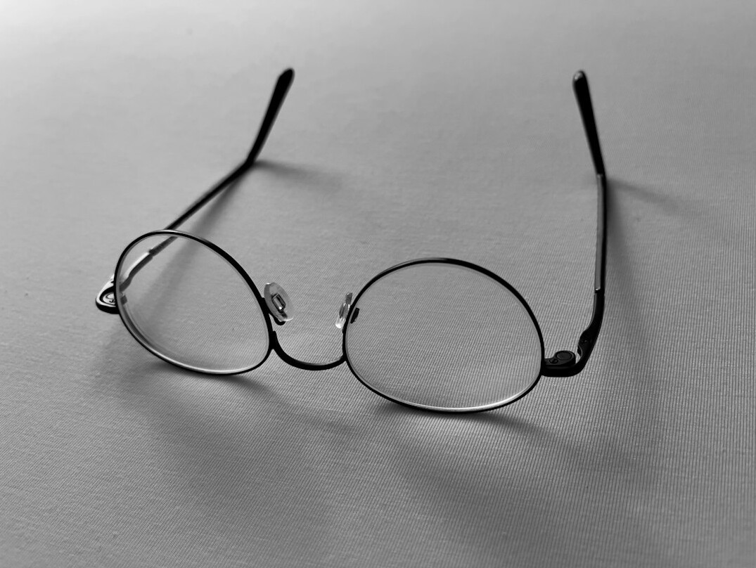 Open book with reading glasses on a wooden table
