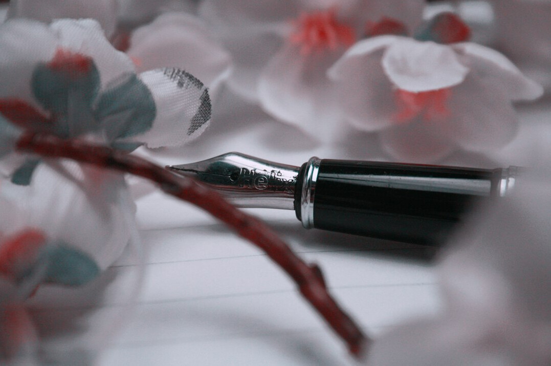 Open fountain pen resting on handwritten manuscript pages
